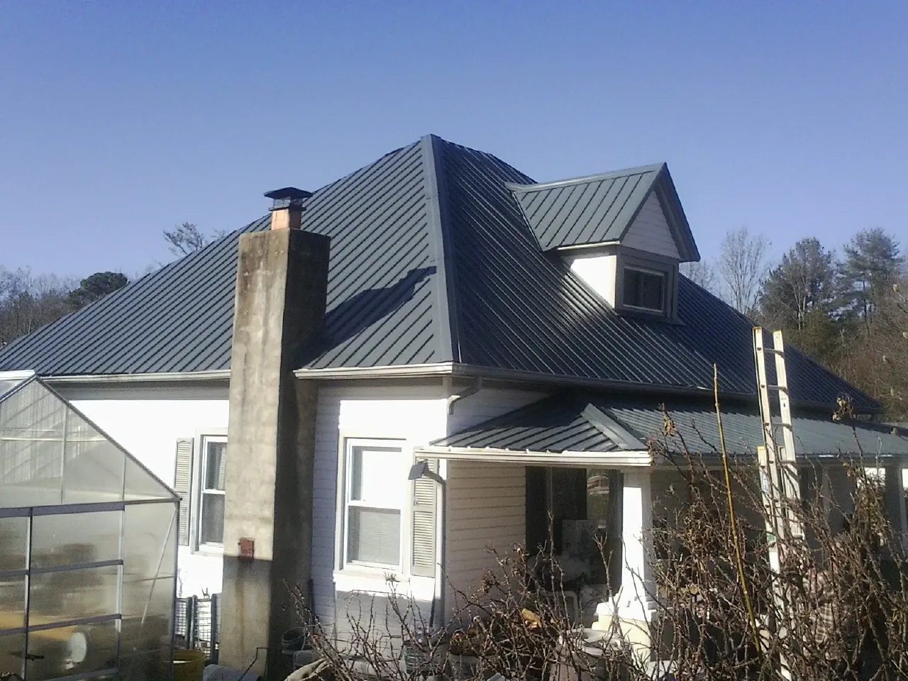 Dark blue standing seam metal roof on a white farmhouse with dormer — Slate & Tile Roof Repair by Roofing Brothers in Roca